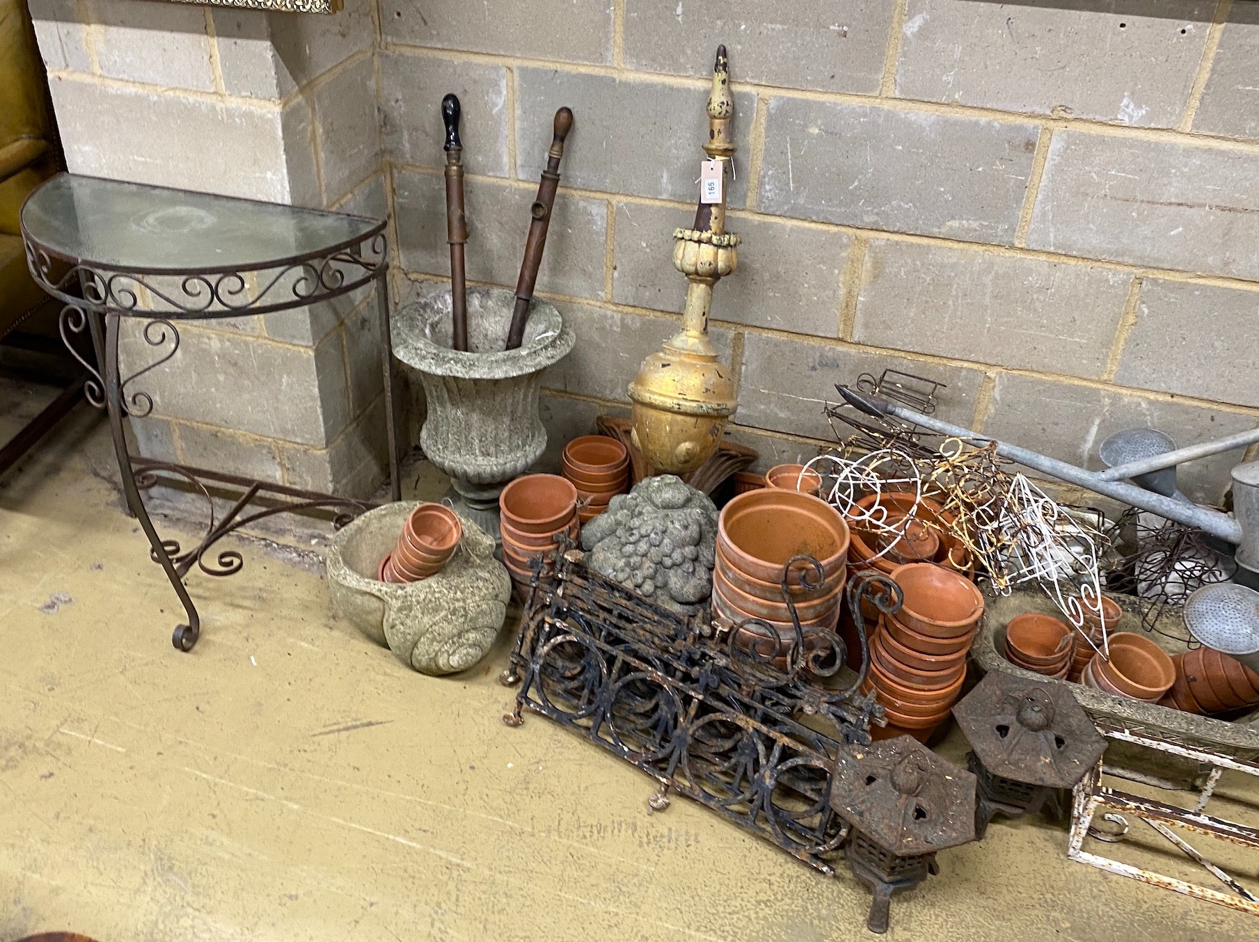 A large quantity of assorted garden ornaments, terracotta pots, galvanised watering cans, bench ends, etc.
